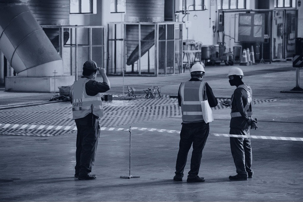 Construction-Worker stretching the red-white warning tape to the pole at a construction site, accidents on construction sites