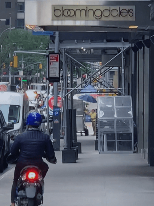 A motorcyclist driving his moped on the sidewalk in front of Bloomingdale’s